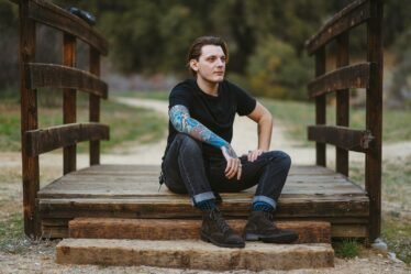 Homme portant un jean en denim brut, assis sur un pont en bois