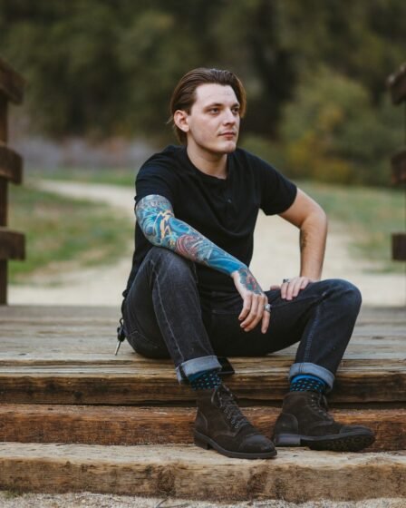 Homme portant un jean en denim brut, assis sur un pont en bois