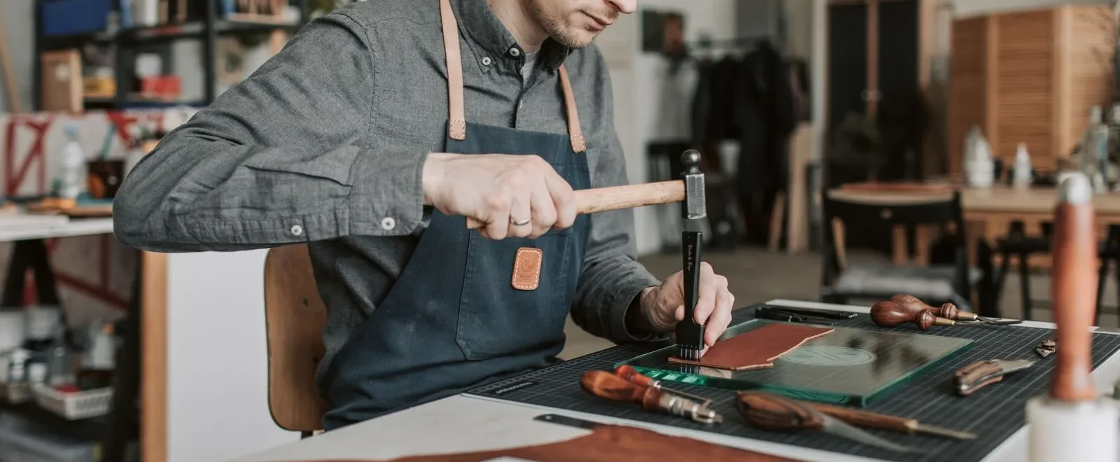 Artisan faconnant une piece de cuir a la main dans un atelier francais