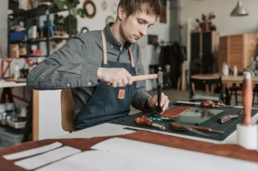 Artisan faconnant une piece de cuir a la main dans un atelier francais
