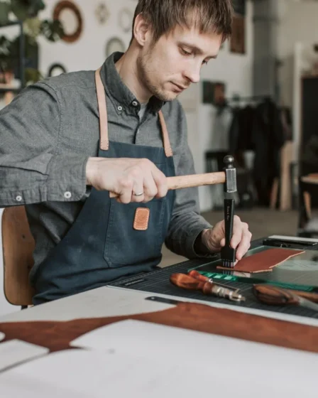 Artisan faconnant une piece de cuir a la main dans un atelier francais