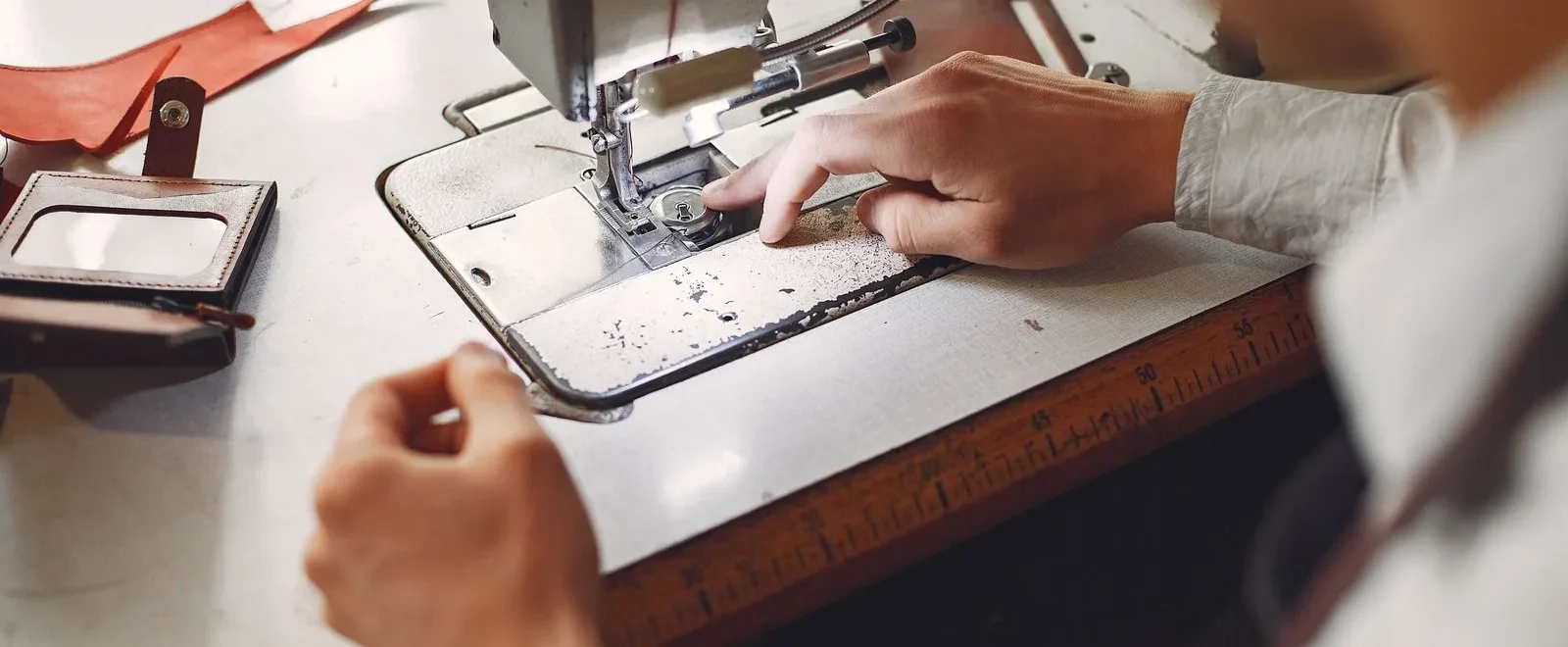 Artisan cousant une piece en cuir a la machine dans un atelier