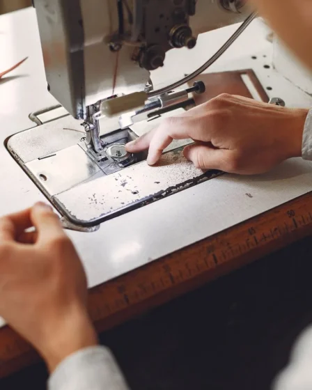 Artisan cousant une piece en cuir a la machine dans un atelier