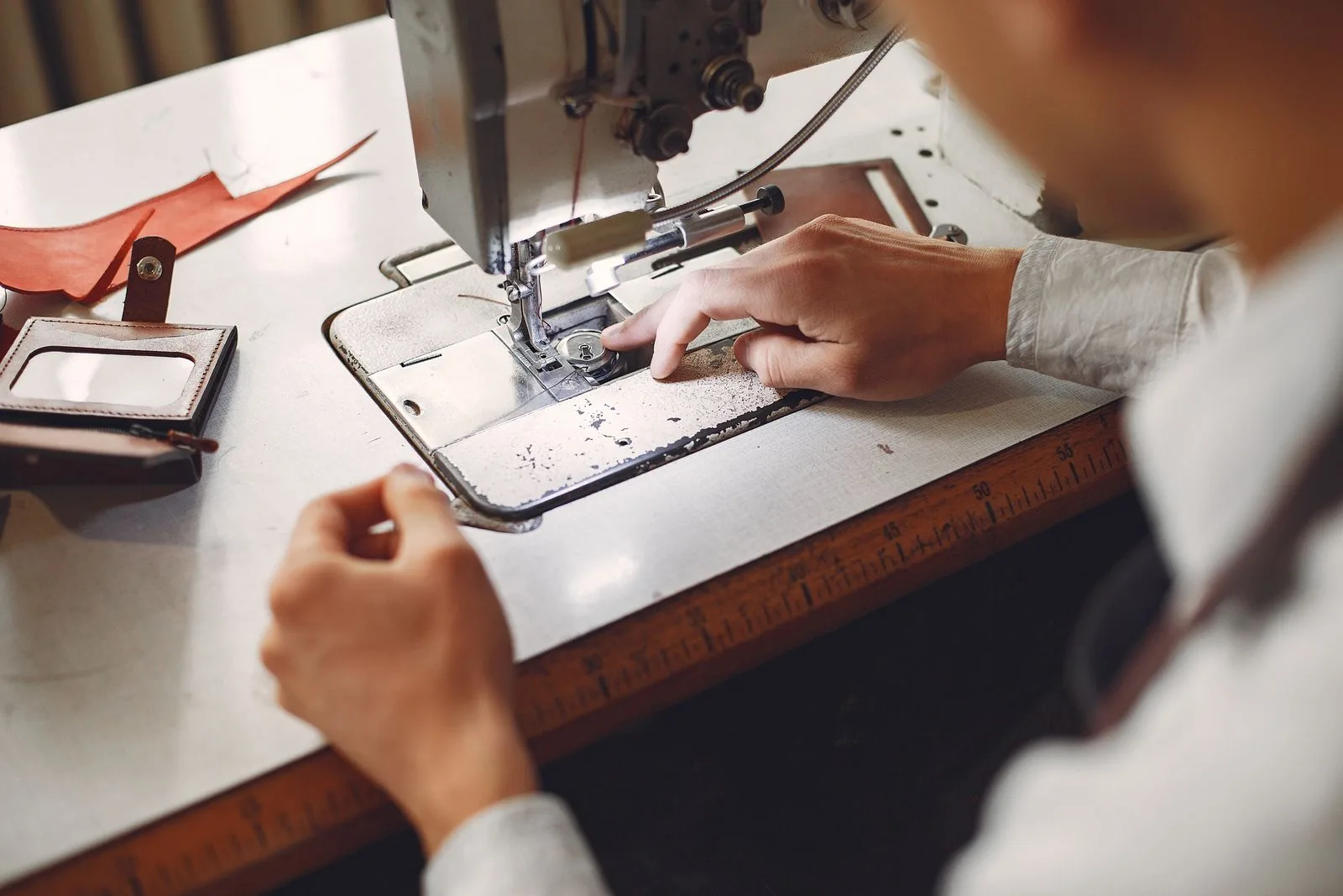 Artisan cousant une piece en cuir a la machine dans un atelier