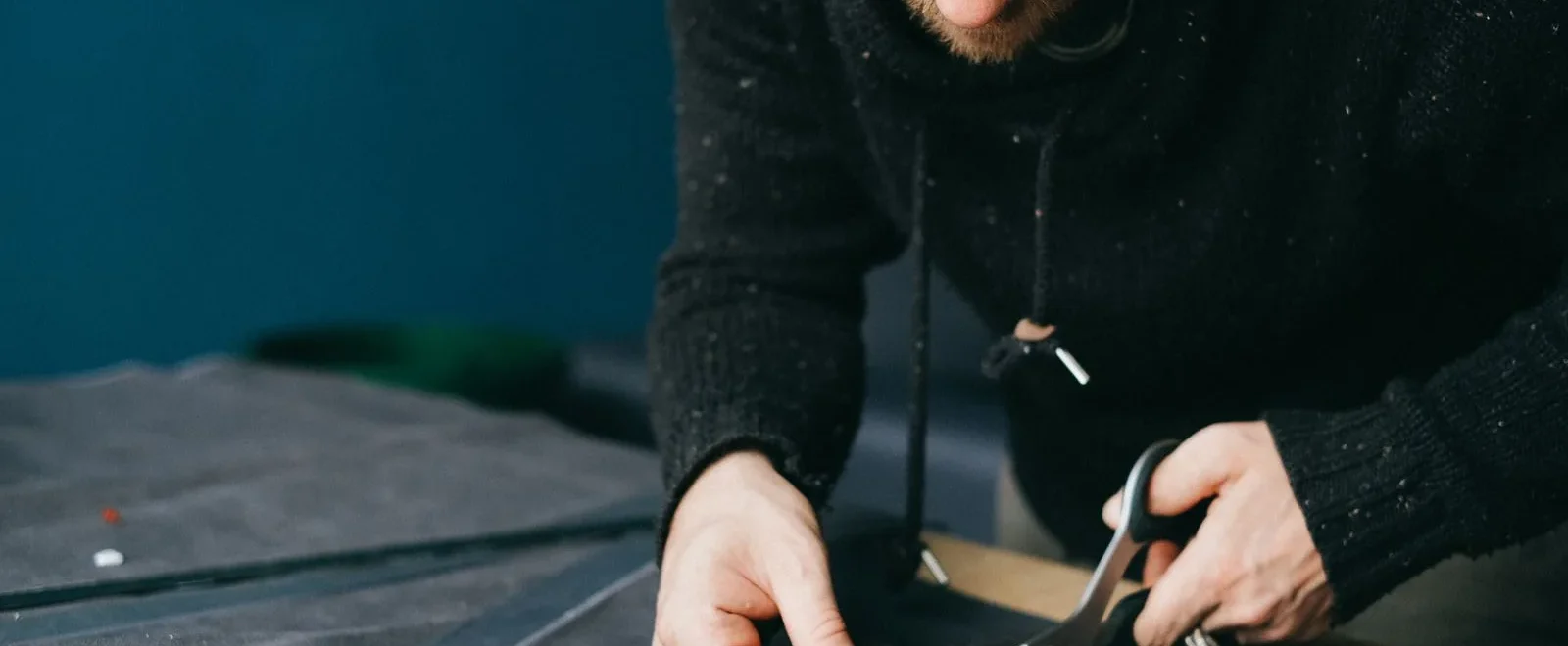 Artisan coupant une piece de cuir aux ciseaux en suivant un patron