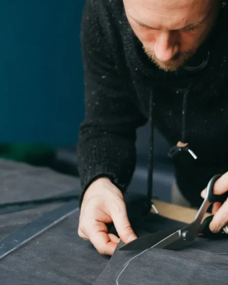 Artisan coupant une piece de cuir aux ciseaux en suivant un patron