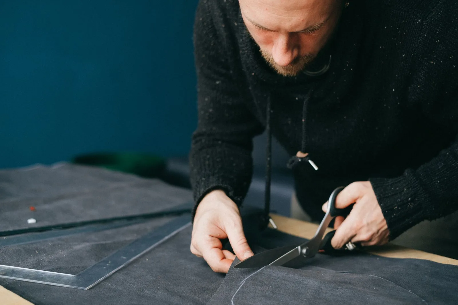 Artisan coupant une piece de cuir aux ciseaux en suivant un patron