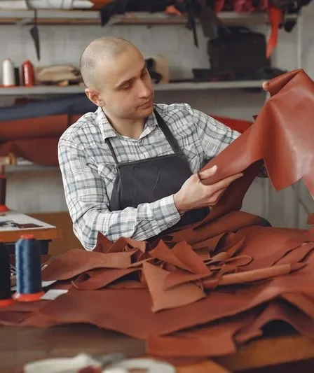 Artisan choisissant une peau de cuir dans un atelier de maroquinerie