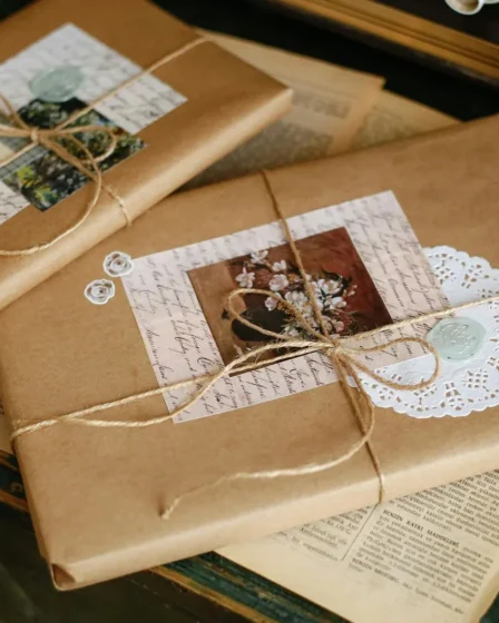 Paquets cadeaux emballés de papier kraft, ficelle et petites images vintage, posés sur de vieux journaux