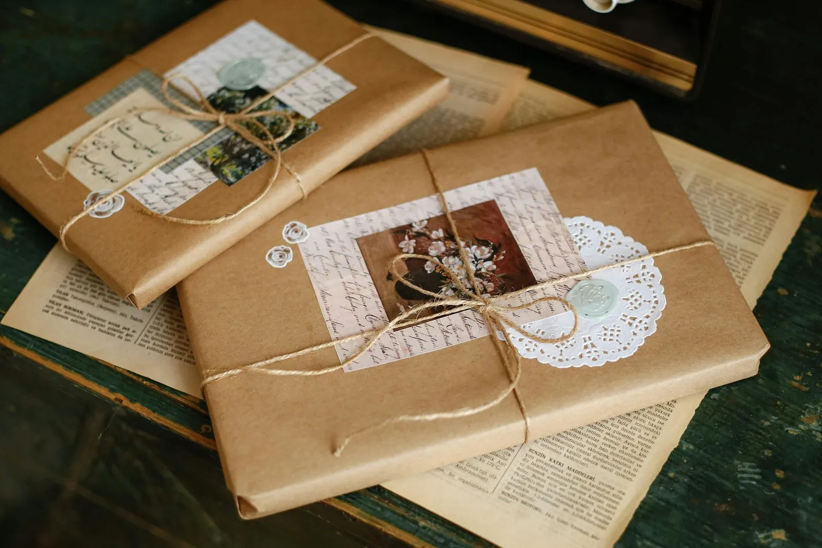 Paquets cadeaux emballés de papier kraft, ficelle et petites images vintage, posés sur de vieux journaux