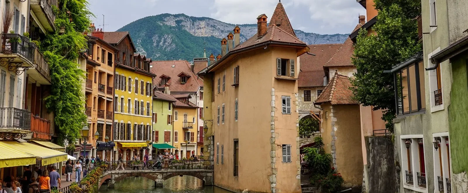 Canal du Thiou et façades colorées de la vieille ville d'Annecy, avec les montagnes en arrière-plan