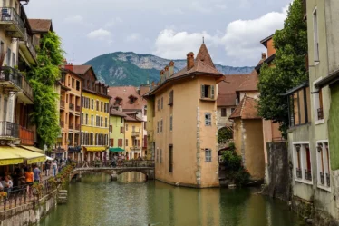 Canal du Thiou et façades colorées de la vieille ville d'Annecy, avec les montagnes en arrière-plan